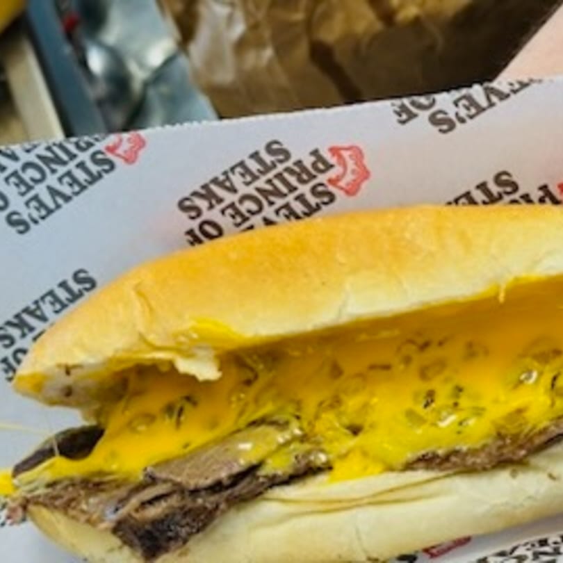 A Steve's Prince of Steaks cheesesteak with melted cheese on a branded wrapper.
